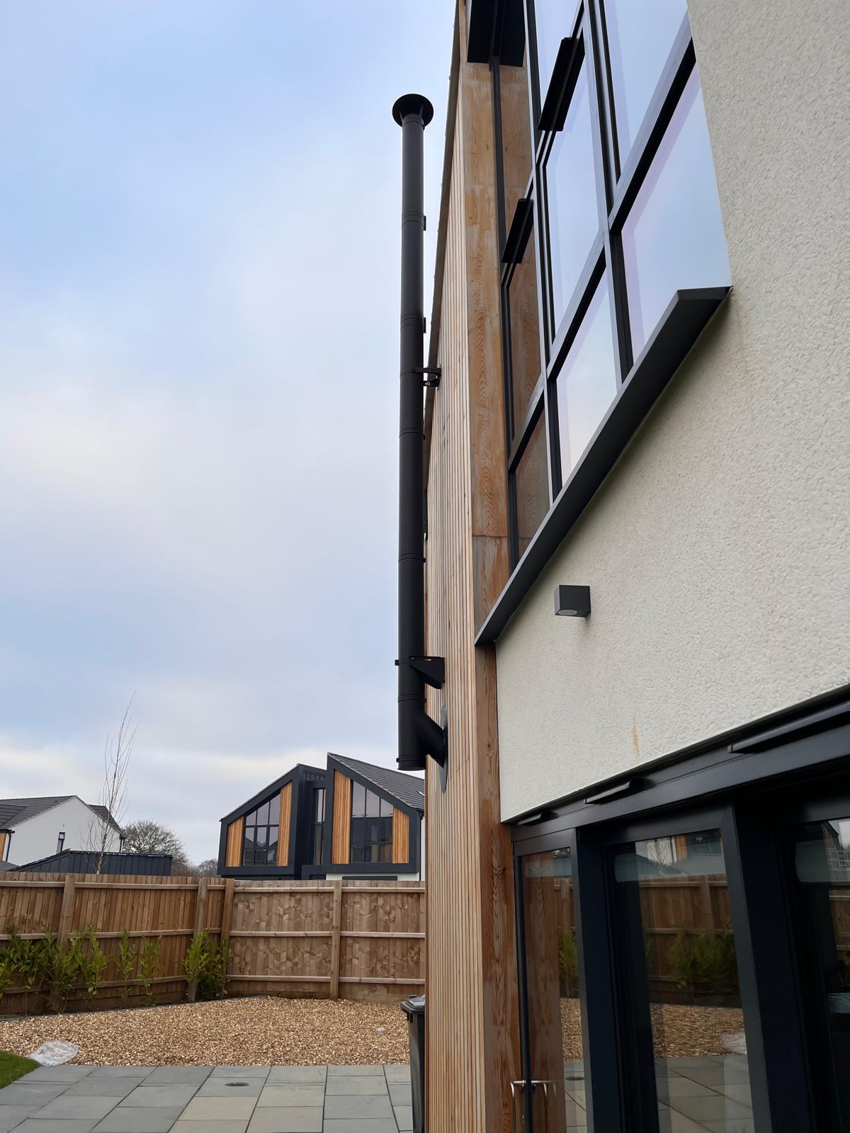 Side view of external flue installation with timber cladding — Norfolk chimney work