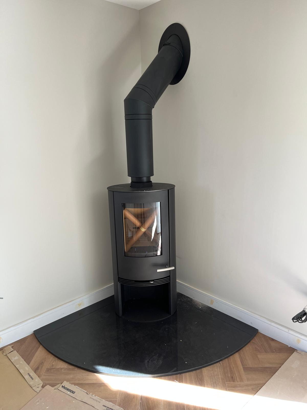 Cylinder wood burning stove on curved black hearth over parquet flooring — Watmore's Woodburners